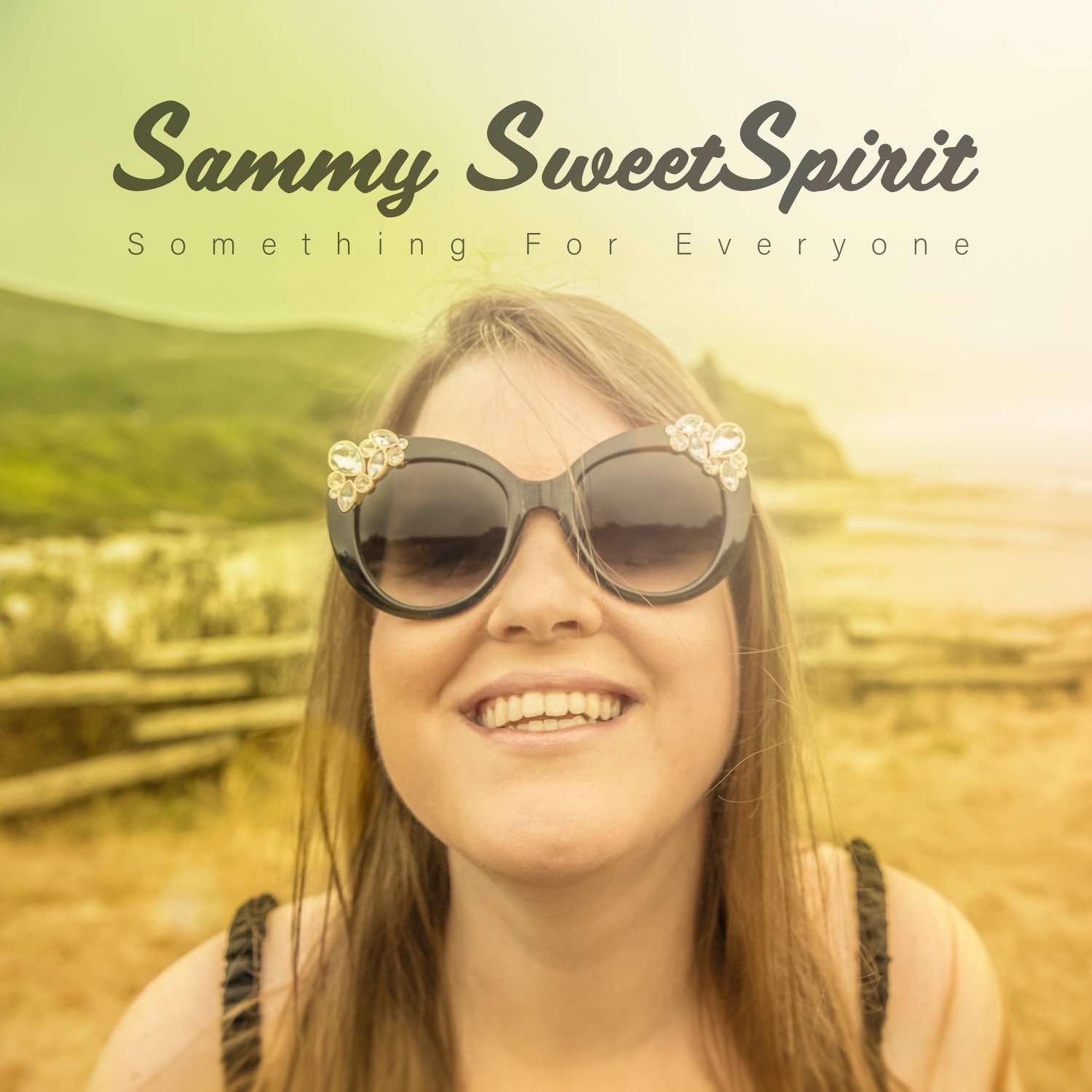 Cover art for 'Sammy SweetSpirit' album titled 'Something For Everyone.' The background has a soft, warm yellow gradient blending into light green, giving a serene outdoor atmosphere. At the top, centered, is the text 'Sammy SweetSpirit' in dark, elegant, cursive font, followed by 'Something For Everyone' in smaller, black, uppercase letters.

The main subject, Sammy SweetSpirit, is positioned in the center of the image. She is smiling brightly, wearing large, round black sunglasses adorned with decorative floral designs at the corners. Her light brown hair falls naturally over her shoulders. The background features a blurred landscape of green hills and a wooden fence, with a sandy area in the foreground, suggesting a coastal or countryside setting. The overall feel of the image is warm and inviting, emphasizing a connection to nature and a sense of joy and openness.